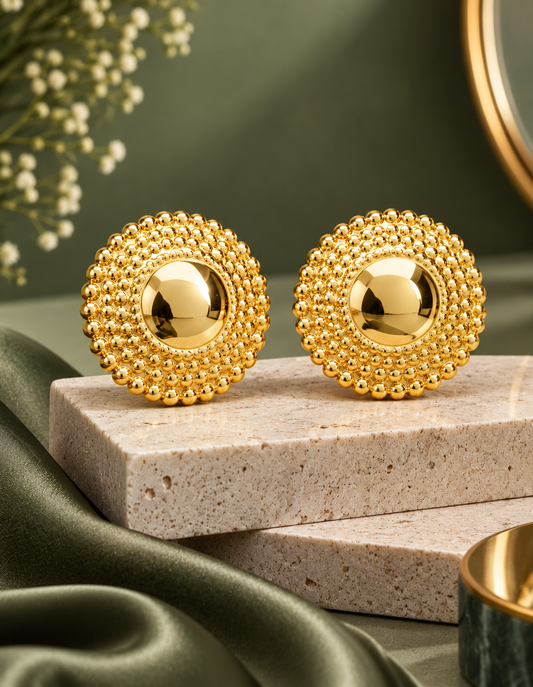 Pair of round gold Nubian Goddess jumbo stud earrings on a rectangular stone display