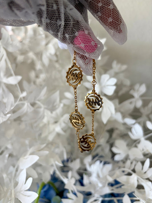 Gold Gye Nyame charm bracelet hanging among white flowers