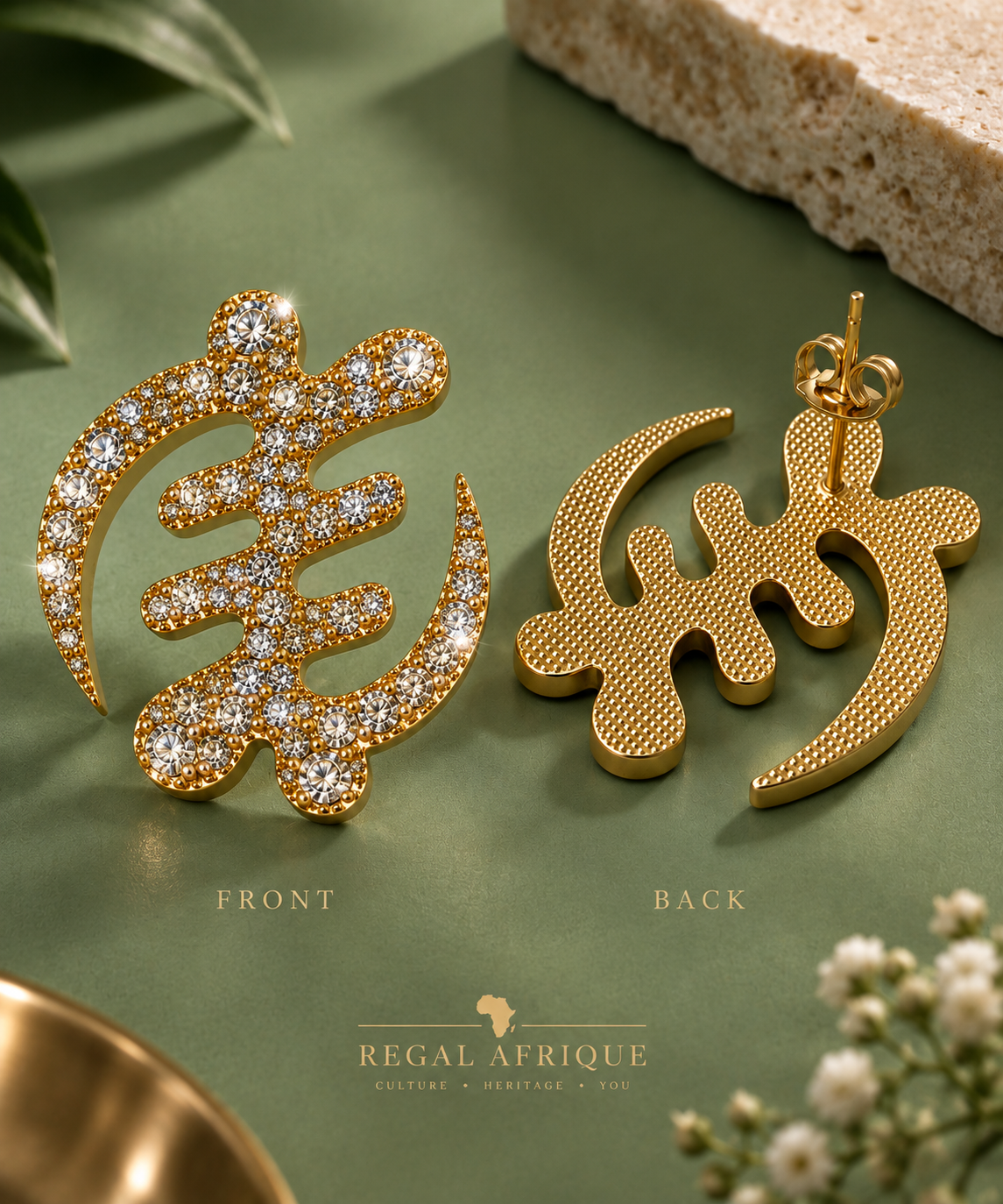 Front and back views of crystal-studded gold Gye Nyame earrings on sage green