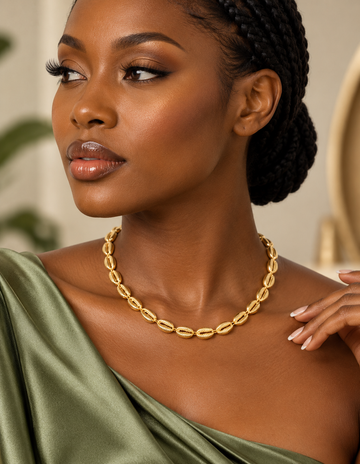 Woman wearing a gold cowrie-link choker necklace with a green top