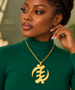 Woman wearing a gold Gye Nyame XL pendant necklace over a green top