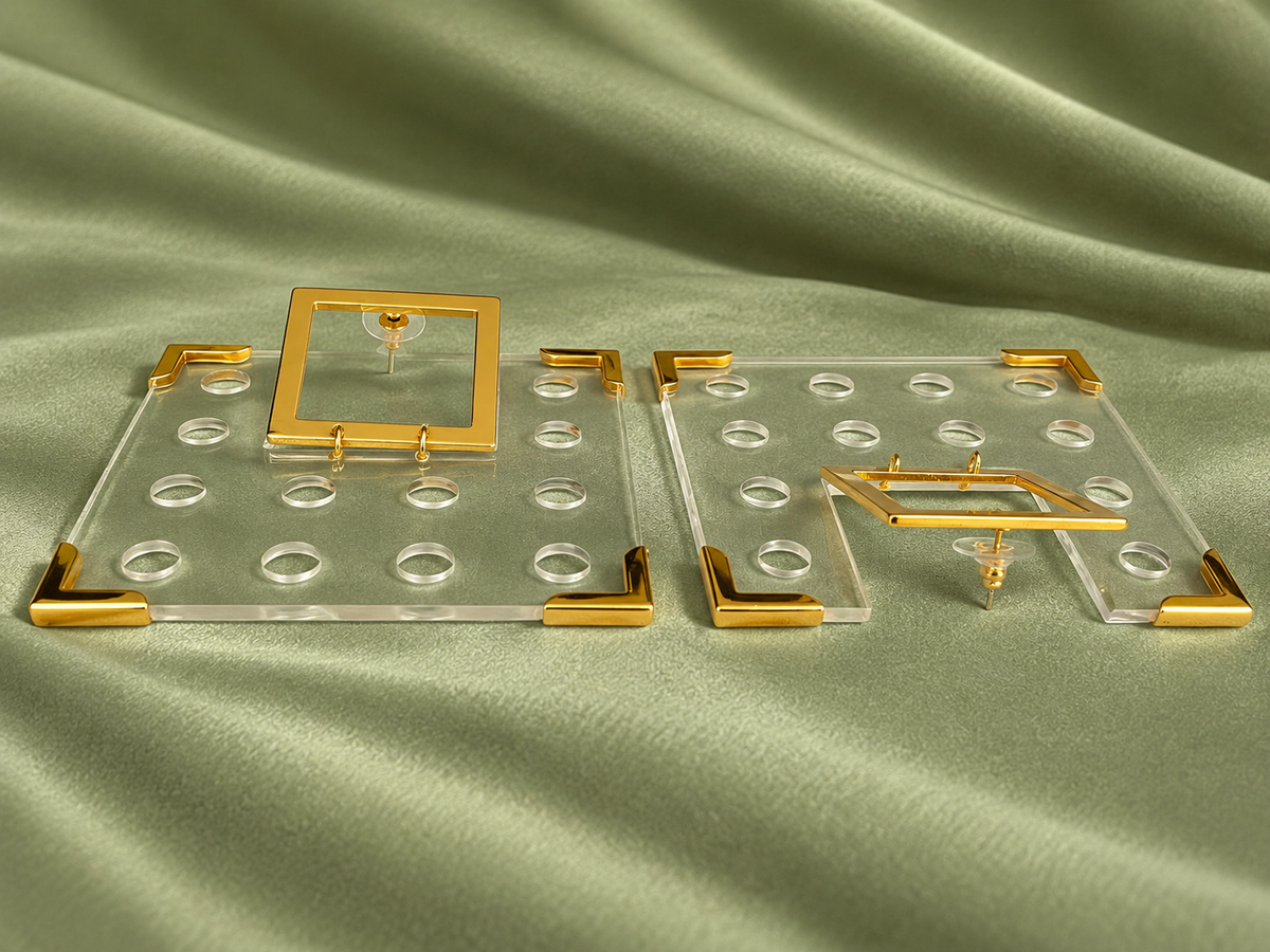 Pair of clear square Geo earrings with gold-tone corners on sage-green fabric