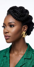 Woman wearing gold Gye Nyame medium stud earrings with a green jacket