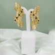 Pair of gold sculptural ribbon earrings with black floral accents