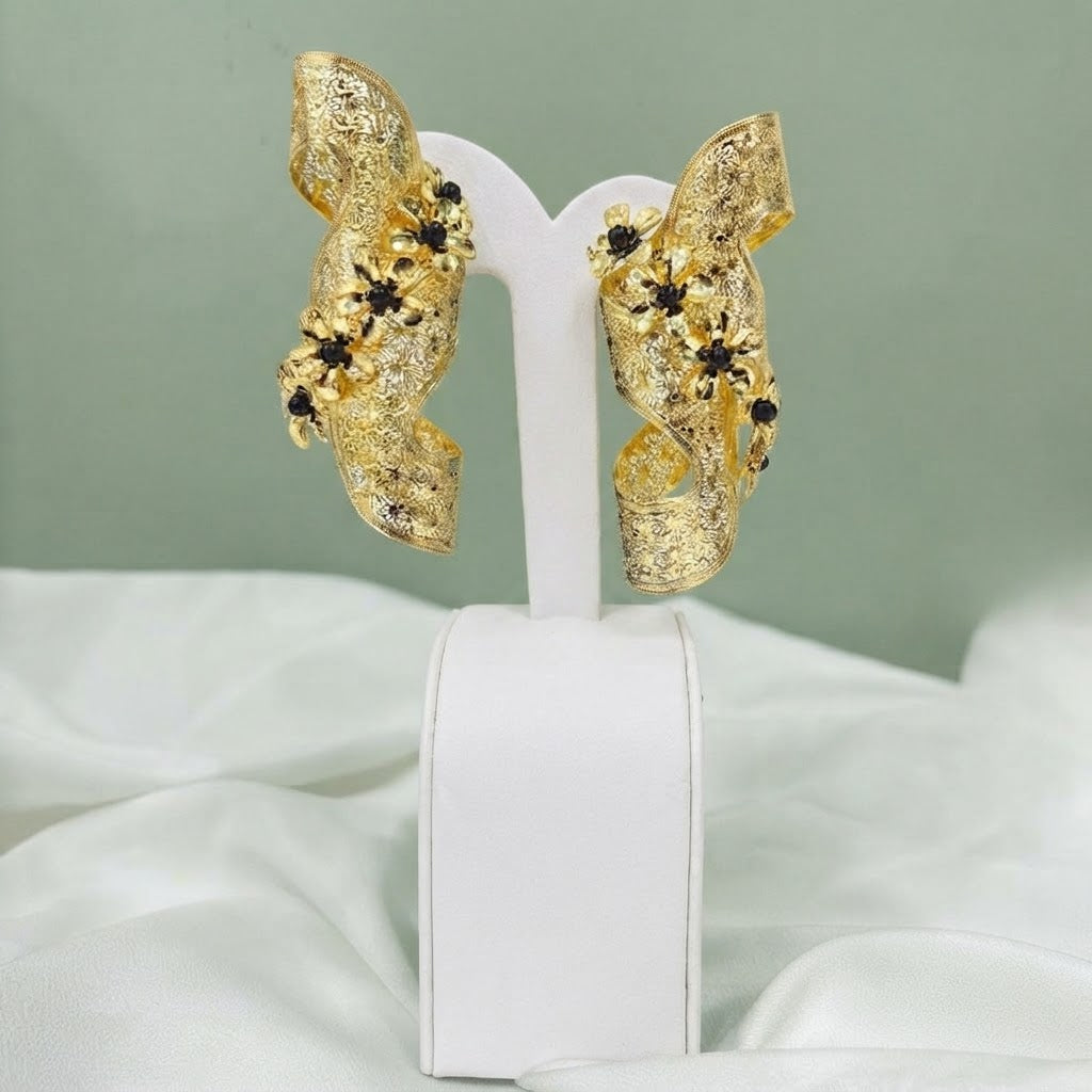 Pair of gold sculptural ribbon earrings with black floral accents
