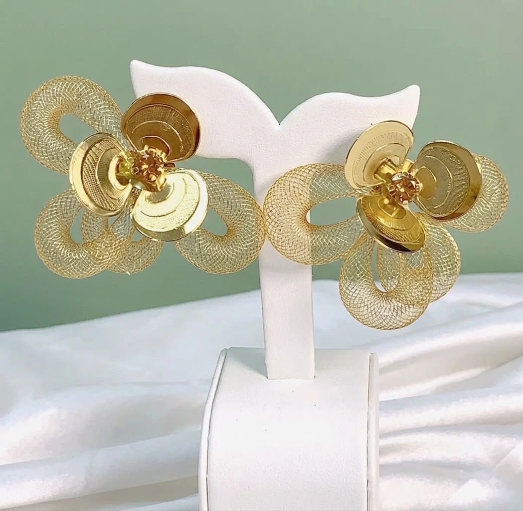 Pair of gold mesh flower earrings displayed on a stand