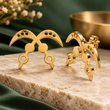 Gold Akofena crossed-sword stud earrings displayed on a stone block