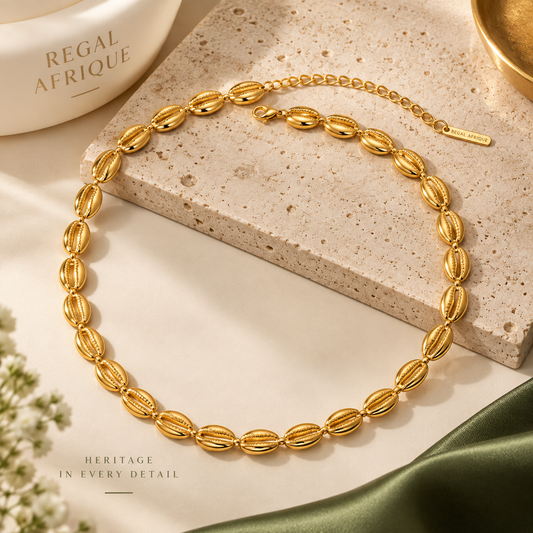 Gold cowrie-link choker necklace with an extension chain arranged on cream-colored stone